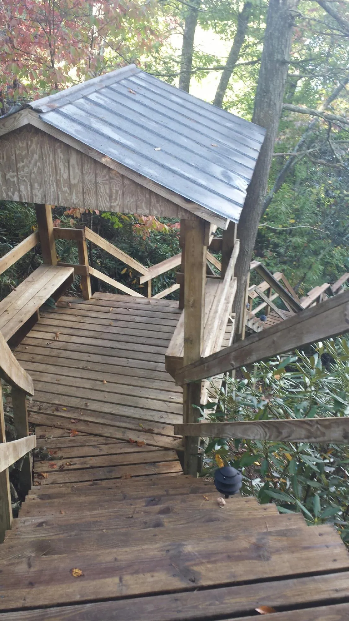 Metal roofed shelter over wooden steps on a wooded walkway — Skylight Repair & Installation work by our crew in Edwards